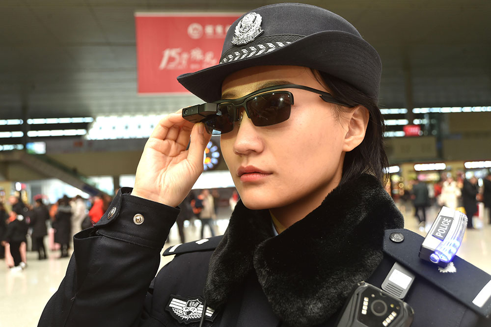 Seorang polisi sedang mengenakan kacamata facial recognition di stasiun kereta api di kota Zhengzhou / QQ