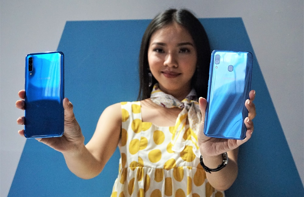 Seorang model tengah memamerkan Samsung Galaxy A50 (kiri) dan Galaxy A30 (kanan).