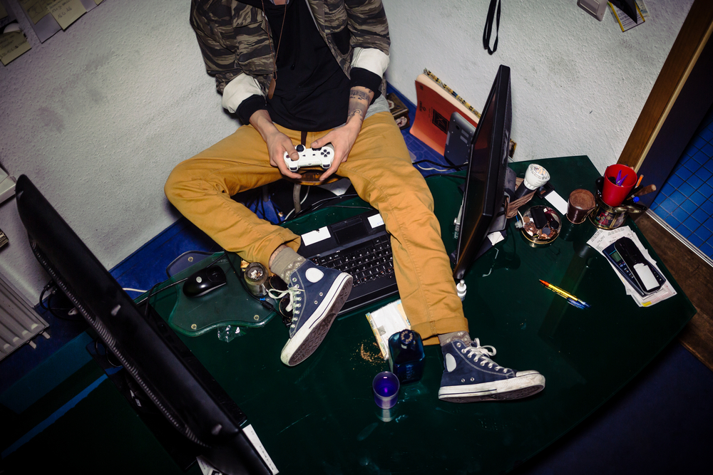 Teenager with video game addiction playing while sitting on a me for SEO